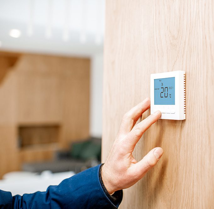 Adjusting room temperature with electronic thermostat at home, close-up view with no face